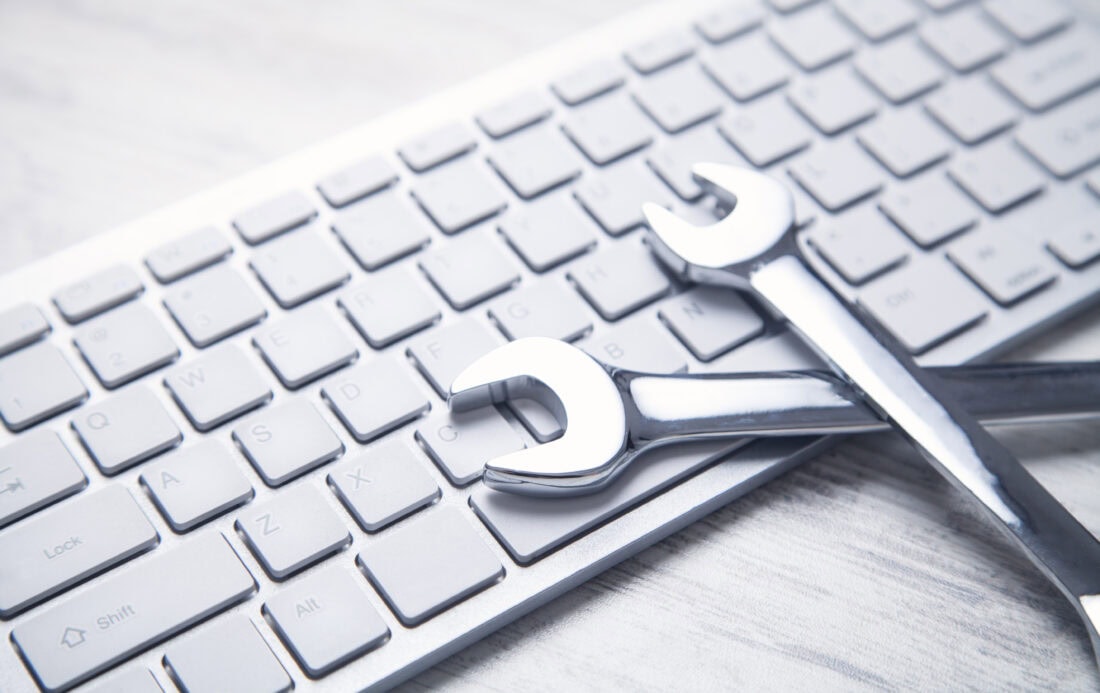 Zwei silberne Schraubenschlüssel liegen über einer Computertastatur
